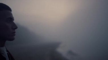 Güneşin doğuşunda deniz kıyısında duran stresli adam. Okyanus havası soluyan yorgun bir adam.