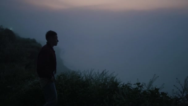 Samotny człowiek spacerujący po górach o wschodzie słońca. Zrelaksowany facet stojący na skalistym wybrzeżu — Wideo stockowe