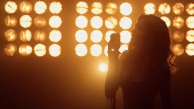 Sarışın vokalist sahnede tutkulu bir şarkı söylüyor. Stüdyoda dans eden kız