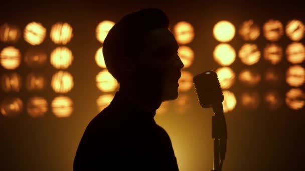Силуэт поющий мужчина вокалист с помощью микрофона на сцене ночного клуба крупным планом — стоковое видео