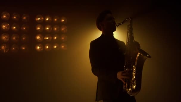 Silueta muž saxofonista hrající na pódium. Chlápek hrající saxofon v klubu. — Stock video
