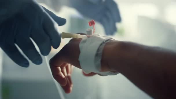 Doctor adjusting medical drip in ward. Patient hand with IV catheter closeup. — Stock Video
