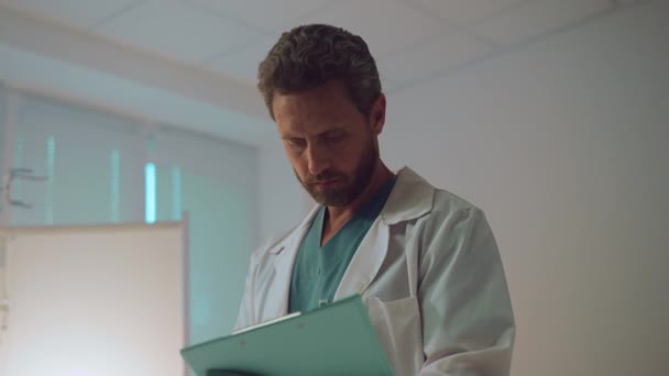 Portrait doctor sostiene portapapeles tomando notas en la unidad de cuidados intensivos del hospital. — Vídeo de stock