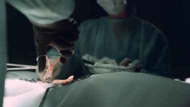 Cerrah elleri hastaya dikiş atıyor. Ekip hastaneyi bitirsin..