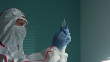 Doktor koruyucu giysinin içinde şırınga aşısı hazırla. Antivirüs sağlık kampanyası