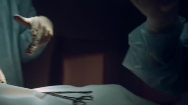 Tıbbi eller operasyonu yakından gerçekleştiriyor. Bilinmeyen hemşire ekipmanları teslim ediyor..