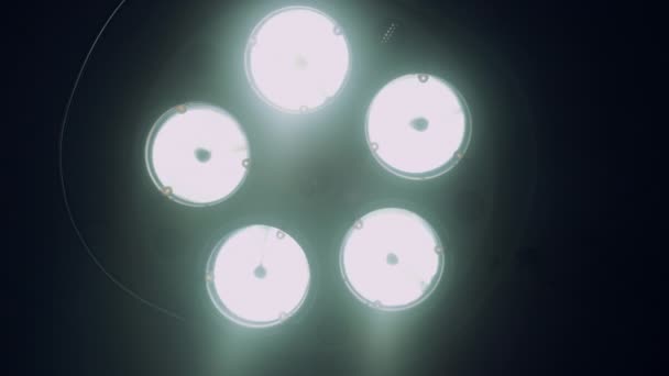 Lâmpada cirúrgica brilhante desligando na sala de cirurgia do hospital escuro de perto. — Vídeo de Stock