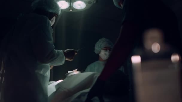 Équipe de chirurgiens opérant dans un service stérile sombre. Travailleurs médicaux sauver le patient. — Video