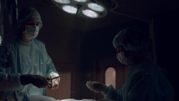 Trabajadores médicos profesionales realizando operaciones en quirófano oscuro. — Vídeo de stock