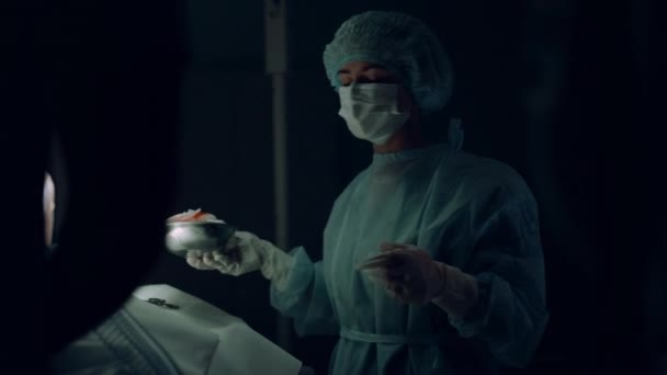 Enfermera entregando instrumentos quirúrgicos ayudando al médico en la sala de emergencias del hospital. — Vídeos de Stock