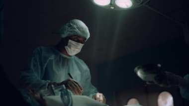 Ciddi bir cerrah koğuşta cerrahi tedavi uyguluyor. Tıbbi ekip işbirliği.