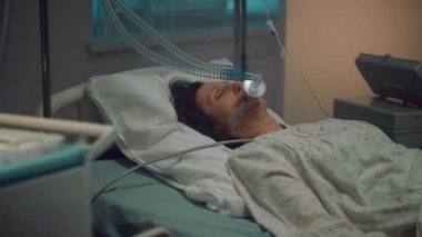 Oksijen maskeli hasta boş hastane koğuşunda yatıyor. Tıbbi araçlar masasını kapatın.