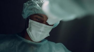 Afrika kökenli Amerikalı cerrah, karanlık klinik portresinde zor bir ameliyat yapıyor..