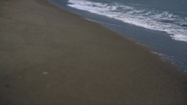 Kumsal dalgaları kıyı şeridini vuruyor. Deniz köpüğü fırtınası mavi kıyı arka planında.