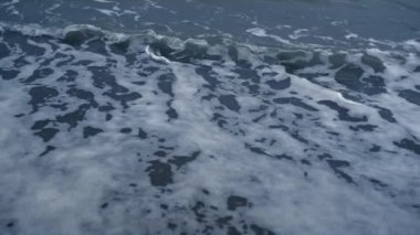 Mavi dalgalar okyanus arka planına çarpıyor. Deniz doğası tsunamisinde su köpüğü sıçrar..