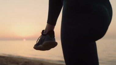 Bilinmeyen kız gün batımında tek bacağını tutuyor. Vücudunu esneten kadın.