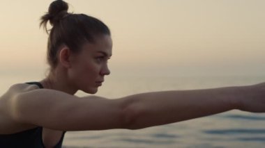 Odaklanan kız ellerini öne uzatıp deniz kıyısında yoga yapıyor.. 