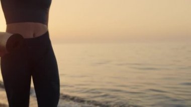 Gün batımında deniz kenarında yürüyen formda bir kız. Sporcu kadın eğitime gidiyor..