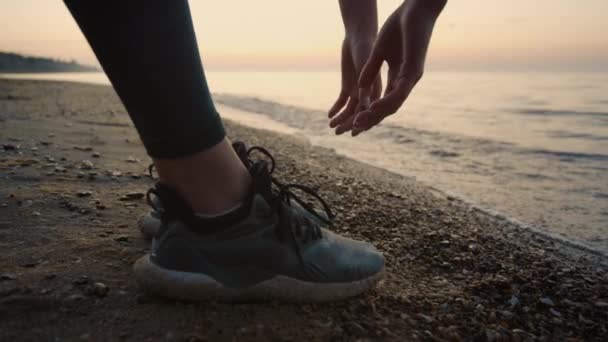 Wanita olahragawan tak dikenal yang meraih tangan ke tanah berdiri di atas pasir dekat. — Stok Video