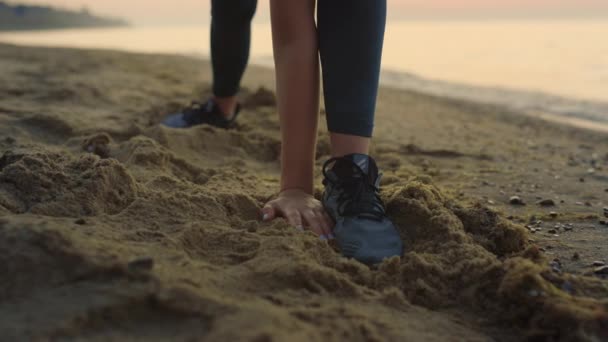 Sportswoman étirant atteindre la main à la jambe en plein air. Fille faire échauffement sur le sable. — Video