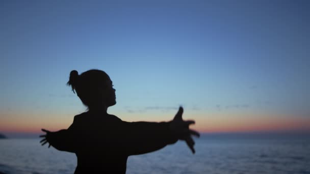 Женщина, занимающаяся йогой, тянется к вечернему небу. Девушка поднимает руки. — стоковое видео