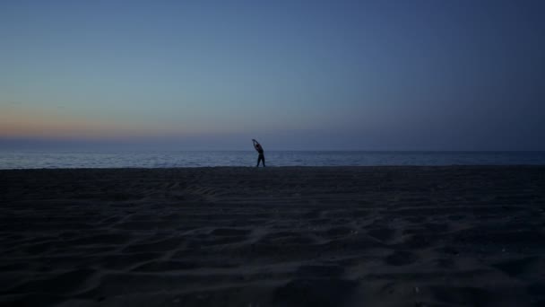 Silhouette donna che fa yoga sulla spiaggia a tarda sera. Ragazza che si estende sulla costa. — Video Stock