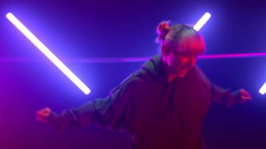Neon ışıklarda serbest dans eden kadın. Sarışın ultraviyole ışıkta atlıyor.
