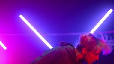 Sarışın sanatçı neon ışıklarda hip-hop dansı yapıyor. Serbest dans eden kız