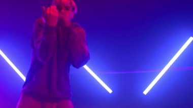 Modern stüdyo ultraviyole ışıkta ritmik hiphop hareketleri yapan adam.. 