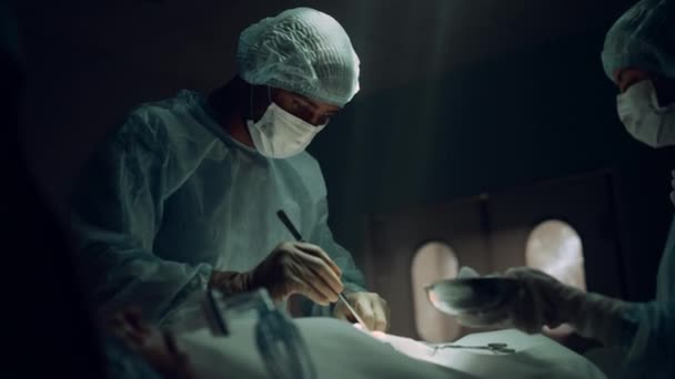 Afrikansk amerikansk kirurg som opererar patienten på en steril akutmottagning. — Stockvideo