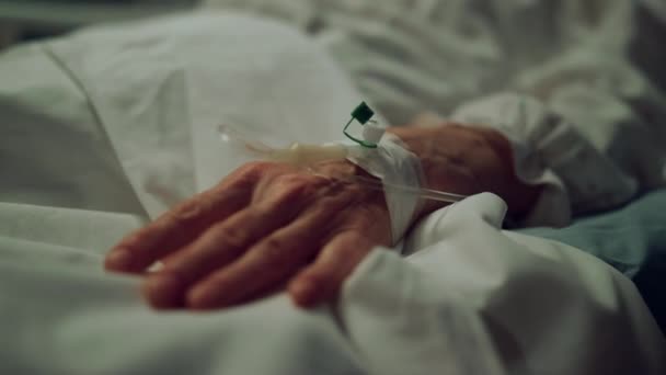 Mão com cateter intravenoso na enfermaria perto da cama. Paciente idoso é submetido a tratamento clínico — Vídeo de Stock
