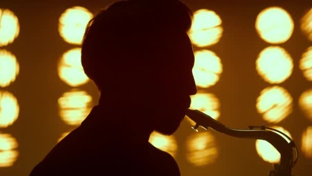 Silhouette guy blowing saxophone on stage closeup. Young saxophonist performing. — Stock Video