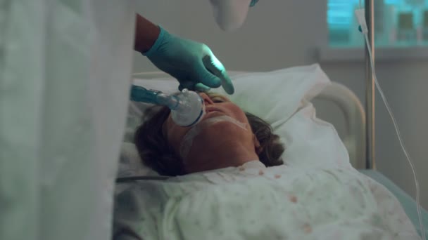 Ill patient breathing oxygen mask hospital bed. Doctor test light reflex closeup — Stock Video