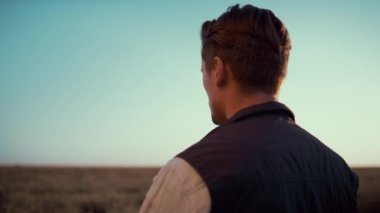 Çiftçi akıllı telefonuyla tarla fotoğrafı çekiyor. Altın sonbahar güneş ışığı arkadan görünüyor..