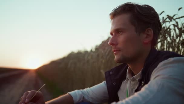 Portret boer eigenaar op zoek in de camera. Zelfverzekerde agrarische rust bij zonsondergang. — Stockvideo
