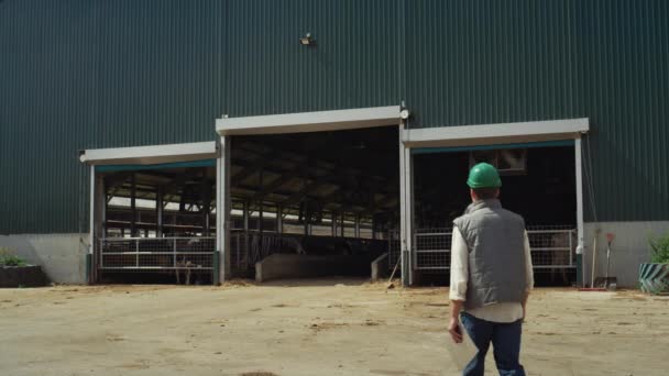 Trabajador caminando granja ganadera instalación sujetando portapapeles. Industria de productos lácteos. — Vídeo de stock