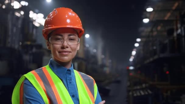 Femeie inginer zâmbind aparat de fotografiat purtând cască de siguranță la depozitare industrială uriașă. — Videoclip de stoc