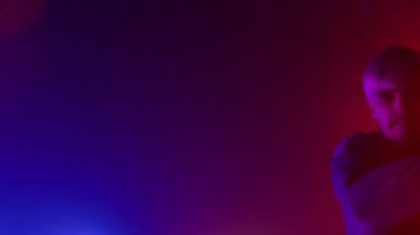 Yakışıklı dansçı, gece kulübünün neon ışıklarında break dans yapıyor..