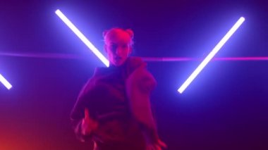 Kız hiphop dansçısı vücudunu morötesi ışıkta hareket ettiriyor.. 
