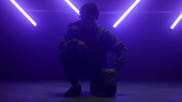 Cool tanečník chlap sedí pózovat sebevědomě na tanečním parketu v nočním klubu světla. — Stock video