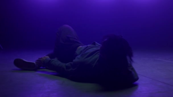 Élégant breakdancer corps mobile couché piste de danse dans les lumières ultraviolettes club. — Video