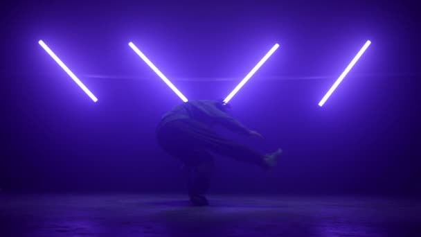 Hombre bailarín realizando hip-hop en luces ultravioletas. Joven b-boy spinning cuerpo. — Vídeo de stock