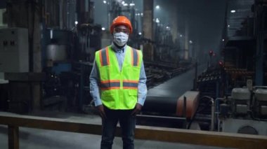 Modern dijital enerji üretim deposunda maskeli bir uzman yüzüne dokunuyor.