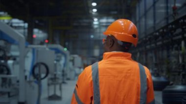 Afro american supervisor walking huge modern energy production factory back view