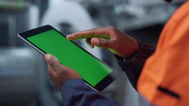 Yeşil ekran tablet mühendisinin elleri fabrikanın yakın çekiminde. Adam sörf maketi ekranı