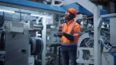 Makine fabrikasında sanal parçaları taşıyan şeffaf tablet tutan denetçi