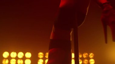 Direğe baş aşağı asılı bir kadın içeride gösteri yapıyor. Direk dansı yapan seksi kız.