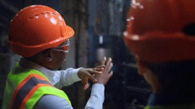 Profesyonel bir erkek tesiste kadın endüstriyel mühendisin yanına yaklaşır..