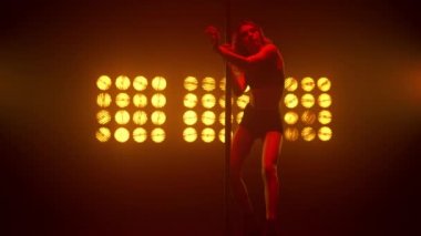 Gece kulübünün sahne ışıkları altında seksi bir şekilde dans eden genç bir kadın..