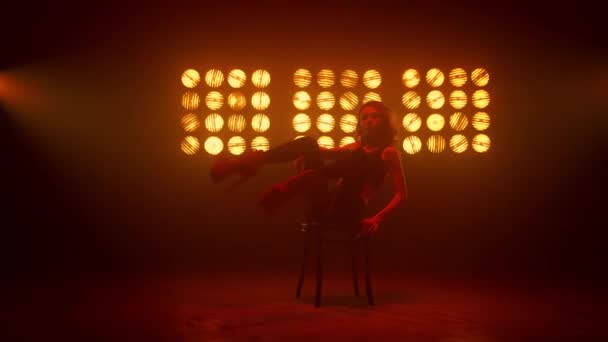 Meisje met erotische bewegingen zittend op een clubstoel. Hot danser verhogen benen. — Stockvideo